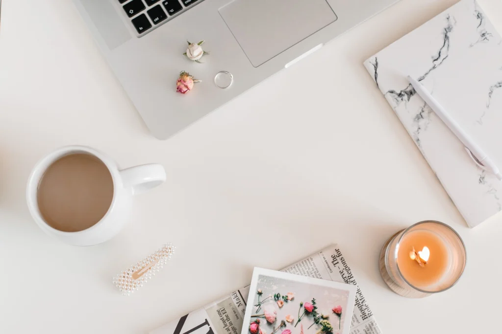 Woman working on desk laptop with jewellery and coffee